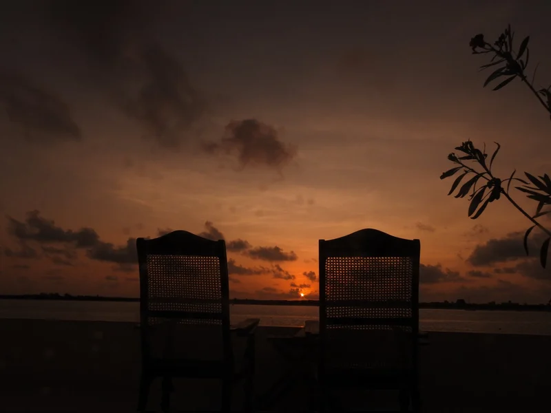 Two chairs on a terrace at dusk, looking out over the water