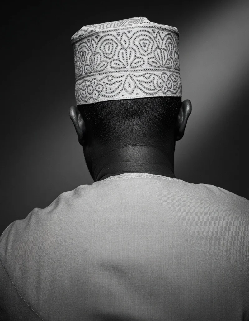 A hand-embroidered white kofia, worn, seen from behind: rows of stitched floral and scroll patterns