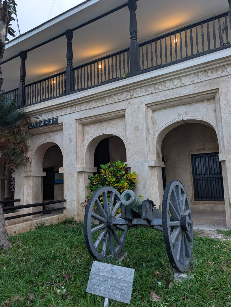 The Lamu Museum: a coral-stone arcade and carved balcony, with an old cannon on the lawn